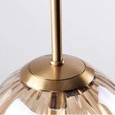 Close-up of a gold pendant light fixture with a clear glass shade on a white background